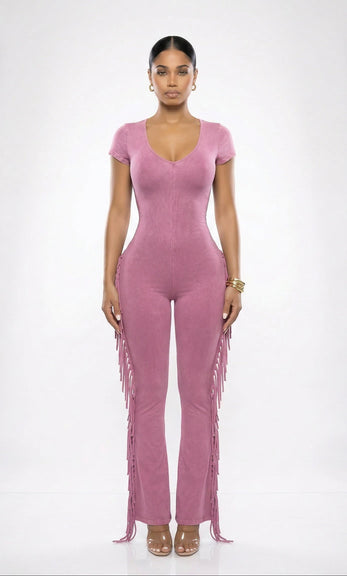 Woman wearing a pink jumpsuit with fringe details on a white background