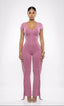 Woman wearing a pink jumpsuit with fringe details on a white background